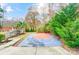 Backyard cement basketball court is surrounded by lush landscaping and a black metal fence at 520 Beacon Knoll Ln, Fort Mill, SC 29708