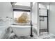 Modern bathroom with soaking tub, walk-in shower, marble tile, and a large window with a view at 520 Beacon Knoll Ln, Fort Mill, SC 29708