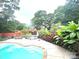 An inground pool and outdoor kitchen surrounded by lush greenery and mature trees at 520 Beacon Knoll Ln, Fort Mill, SC 29708