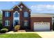 Classic red brick two-story home featuring a two-car garage, dark shutters, and manicured lawn at 903 Furman Ct, Fort Mill, SC 29708