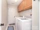 Functional laundry room with front load washer and dryer, storage, and door to hallway at 9051 Country Barn Ct, Charlotte, NC 28273