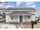 Charming gray home boasts a covered front porch with columns and a classic rocking chair at 92 Saint Charles Ne Ave, Concord, NC 28025