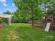 Large backyard with a pergola, patio furniture, mature tree and wooden playset with slide at 1014 Harrogate Ln, Matthews, NC 28104