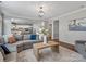 Bright living room with gray sectional sofa, wooden coffee table, and view into the kitchen at 1014 Harrogate Ln, Matthews, NC 28104