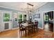 Dining room with hardwood floors, a modern chandelier, and a large window overlooking the outdoor greenery at 10545 Mount Holly Huntersville Rd, Huntersville, NC 28078