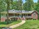 Beautiful brick home featuring a spacious front porch, lush landscaping, and solar panels on the roof at 10545 Mount Holly Huntersville Rd, Huntersville, NC 28078