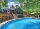 View of the pool with an outdoor deck that has seating areas and an overhead screened porch for enjoying the surrounding greenery at 10545 Mount Holly Huntersville Rd, Huntersville, NC 28078