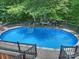 Outdoor pool area featuring an in-ground pool, a deck with railings, and a table and benches set up near a tree for relaxation at 10545 Mount Holly Huntersville Rd, Huntersville, NC 28078