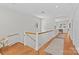 Upstairs hallway featuring hardwood floors, white walls, and wooden railing at 1200 Rutledge Ave, Charlotte, NC 28211