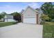 Exterior view of a home showcasing a two-car garage with driveway and beautifully landscaped front yard at 16337 Greybriar Forest Ln, Charlotte, NC 28278