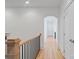 Bright hallway featuring hardwood floors, white walls, wood railing, and elegant arched doorway at 18207 Shearer Rd, Davidson, NC 28036