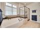 Modern bathroom with tub, frameless glass shower, tile surround, and large window at 18311 Rosapenny Rd, Charlotte, NC 28278