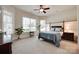 Bright bedroom with large windows, neutral decor, and a four-poster bed with a ceiling fan at 18311 Rosapenny Rd, Charlotte, NC 28278