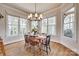 Sunlit dining nook boasts bay windows, a chandelier, hardwood floors, and a charming table set for six at 18311 Rosapenny Rd, Charlotte, NC 28278