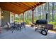 Covered outdoor patio area with seating, barbeque and view into the wooded back yard at 18311 Rosapenny Rd, Charlotte, NC 28278
