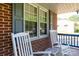 Inviting front porch featuring brick facade, white rocking chairs, and large windows with shutters at 205 Wrentree Ln, Gastonia, NC 28056