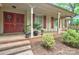 Inviting covered front porch with brick steps, a vibrant red door, and classic columns enhancing the entrance at 3430 Rea Rd, Charlotte, NC 28226