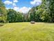 Lush backyard with mature trees providing shade, featuring a brick structure with outdoor cooking setup at 4628 Dovefield Ln, Kannapolis, NC 28081
