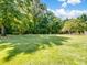 Lush green backyard featuring a well-manicured lawn surrounded by mature trees, creating a serene outdoor space at 4628 Dovefield Ln, Kannapolis, NC 28081