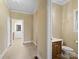 Hallway leading to bathroom featuring tiled floors, vanity, and natural light from a window at 4628 Dovefield Ln, Kannapolis, NC 28081
