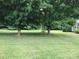 Lush green front yard featuring mature trees that create a cool shaded space in a peaceful residential setting at 609 E Church St, China Grove, NC 28023