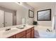 Bathroom with double sinks, garden tub, framed mirror, and neutral decor at 6335 Ziegler Ln, Charlotte, NC 28269
