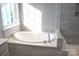 Luxurious bathroom featuring a soaking tub, tile surround, and natural light from a large window at 745 Garrett Green Way, Fort Mill, SC 29715