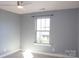 Bright bedroom with neutral walls, carpet, and a large window, enhanced by a ceiling fan with light fixture at 745 Garrett Green Way, Fort Mill, SC 29715