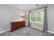 Bright bedroom featuring plush carpet, natural light from the window, and a classic wooden dresser at 8227 Lansford Rd, Charlotte, NC 28277