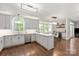 Bright kitchen featuring gray cabinets, stainless steel appliances, hardwood floors, and an adjacent dining area at 8227 Lansford Rd, Charlotte, NC 28277