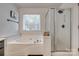 A bright bathroom featuring a soaking tub under a window and a glass-enclosed shower with dark hardware at 1140 Landsdown Dr, Salisbury, NC 28147