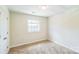 A carpeted bedroom has a white trim window bringing natural light into the space at 1215 Green Oaks Ln # H, Charlotte, NC 28205
