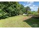 Large backyard featuring lush greenery, mature trees, a wooden deck, and ample space for outdoor activities and relaxation at 1221 Woodpecker Dr, Clover, SC 29710