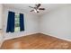 Cozy bedroom with hardwood floors, a ceiling fan, a window dressed with blue curtains, and neutral paint, creating a serene retreat at 1221 Woodpecker Dr, Clover, SC 29710