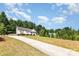 A long driveway leads to this home nestled in a spacious, wooded lot under a blue sky at 1221 Woodpecker Dr, Clover, SC 29710