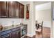 Butler's pantry including wine refrigerator, tile backsplash, and dark wood cabinets at 13204 Feale Ct, Charlotte, NC 28278