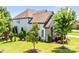 Charming home exterior features manicured lawn, lush trees, neutral paint, and architectural details creating a welcoming curb appeal at 13204 Feale Ct, Charlotte, NC 28278