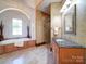Elegant bathroom with soaking tub, granite counters, decorative mirror, and tiled floors at 200 Waterby Way, Matthews, NC 28104