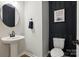 Modern powder room with pedestal sink, stylish mirror and dark accent wall at 2062 Nellies Way, Fort Mill, SC 29715
