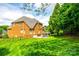 Expansive backyard view showcasing a well-kept lawn, brick home, stone patio and privacy fence at 208 Mcduffie Ln, Fort Mill, SC 29715
