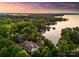 Aerial view of a beautiful waterfront home surrounded by lush trees at sunset on a beautiful lake at 2288 Brawley School Rd, Mooresville, NC 28117
