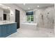 Bright bathroom featuring a soaking tub, walk-in shower, and blue vanity with modern fixtures at 2288 Brawley School Rd, Mooresville, NC 28117