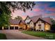 Charming stone and stucco home featuring a three-car garage, brick driveway, and beautiful landscaping at sunset at 2288 Brawley School Rd, Mooresville, NC 28117