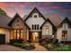 Gorgeous stone and stucco home featuring a brick walkway, lush landscaping, and beautiful windows at twilight at 2288 Brawley School Rd, Mooresville, NC 28117