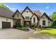 Stately home featuring a stone and stucco facade, a brick walkway, beautiful landscaping, and large windows at 2288 Brawley School Rd, Mooresville, NC 28117