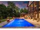Stunning pool and outdoor area with expansive patio, outdoor kitchen, spa and a lush tree line at sunset at 2288 Brawley School Rd, Mooresville, NC 28117