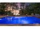 Captivating pool with lake views, surrounded by elegant stonework and lush landscaping at dusk at 2288 Brawley School Rd, Mooresville, NC 28117