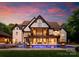Luxury home featuring a large backyard with a pool, fire pits, and patio under a covered porch at sunset at 2288 Brawley School Rd, Mooresville, NC 28117