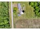 Aerial view showcases a home with outbuildings nestled among trees and adjacent to fields at 335&315 Graham Rd, Mt Ulla, NC 28125
