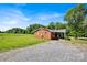 A charming one-story brick home with a gravel driveway and covered parking, set in a lush, green landscape at 335&315 Graham Rd, Mt Ulla, NC 28125